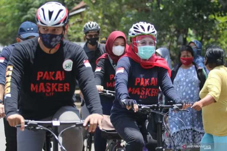 Gubernur Jawa Timur Khofifah Indar Parawansa (kanan) didampingi Wali Kota Kediri Abdullah Abu Bakar (kiri) mengayuh sepeda di Kota Kediri, Jawa Timur, Sabtu (3/10/2020). Bersepeda saat kunjungan kerja tersebut dilakukan Gubernur Jatim untuk mensosialisasikan penggunaan masker di tengah masyarakat guna memutus mata rantai penyebaran COVID-19. ANTARA FOTO/Prasetia Fauzani/hp.